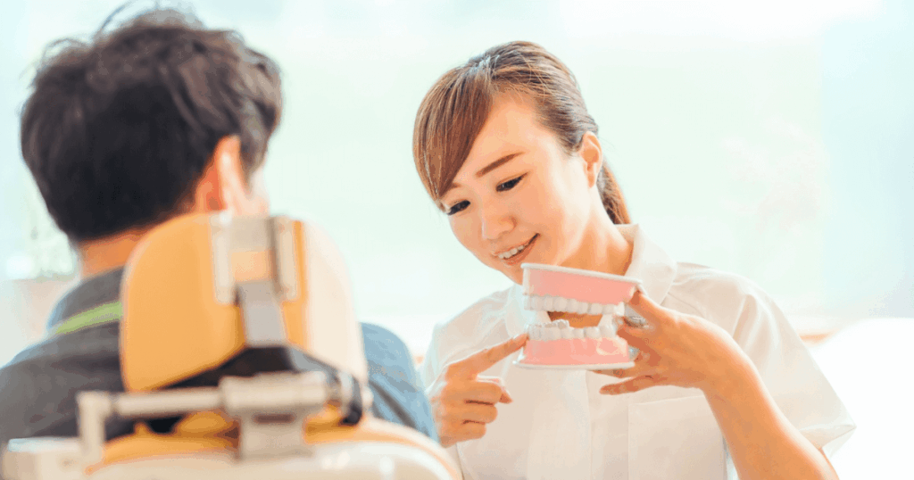 歯科医院で歯の模型を使って説明する女性歯科医と患者