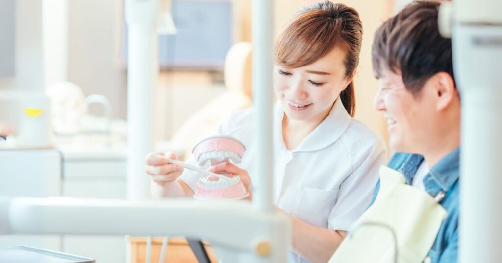 歯科医院で歯科医と笑顔で相談する患者の写真