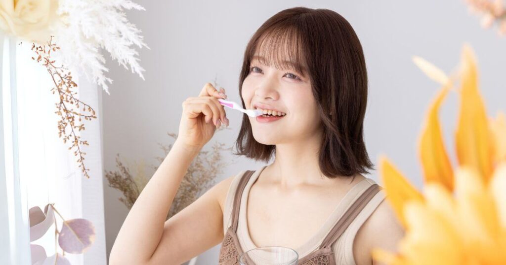 笑顔で歯磨きをする女性とコップの水