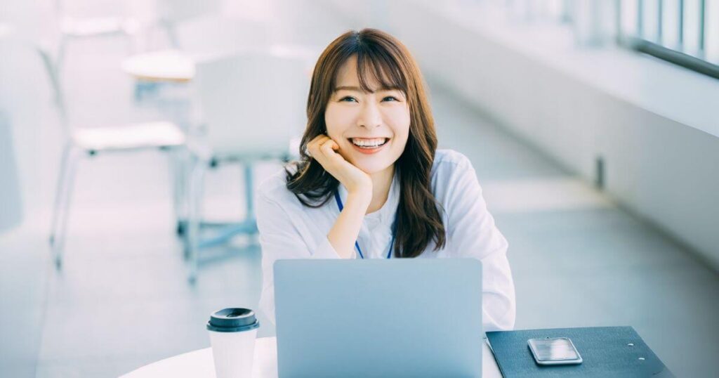 パソコンの前で笑顔を見せる女性。歯の健康を取り戻し、安心して日常を過ごす様子
