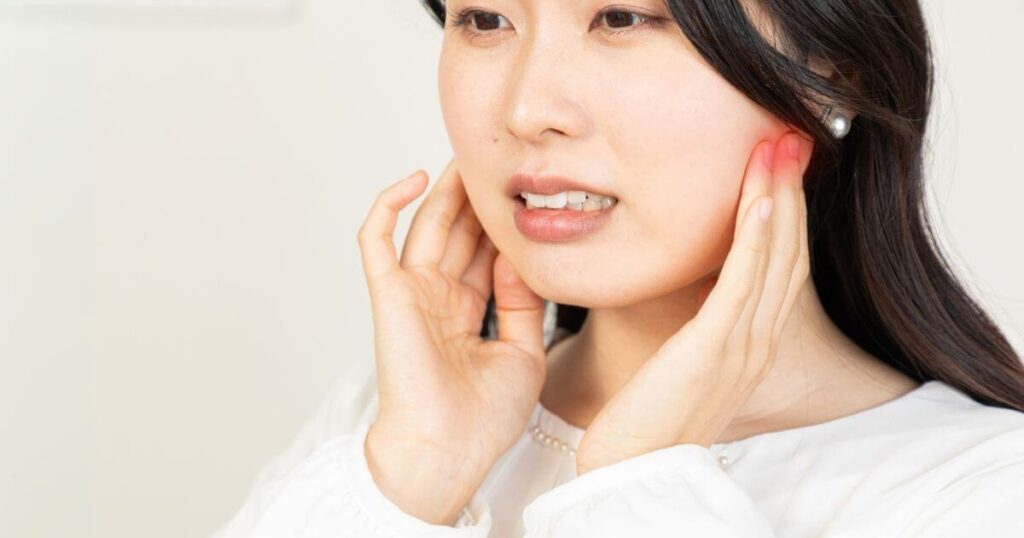 頬の痛みを和らげるツボ「頬車」を押している女性の写真