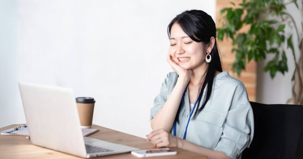 仕事中に歯の痛みで顔を押さえる女性