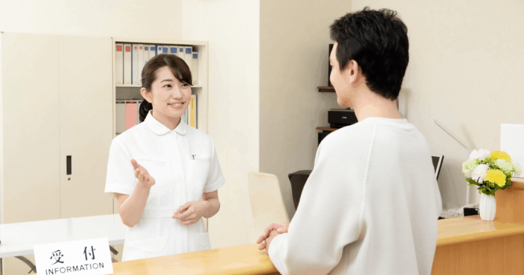 病院の受付で相談する男性とスタッフ