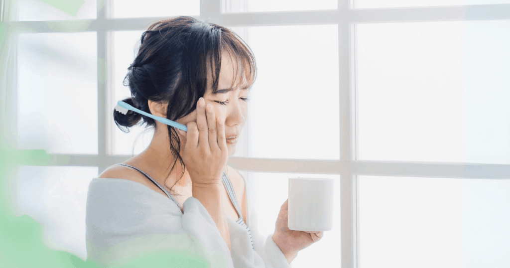 歯の痛みで頬を押さえる女性とコップを持つ様子