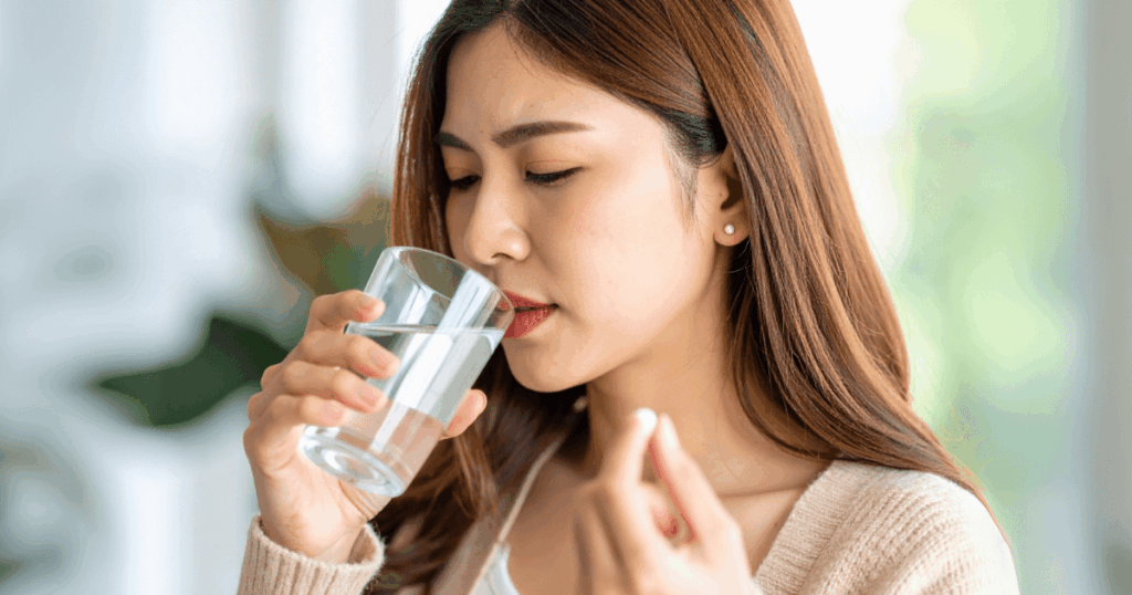水と一緒に鎮痛薬を服用する女性