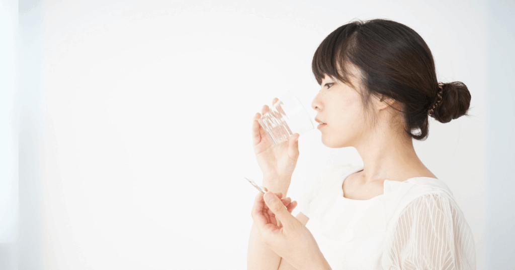 歯の痛みをやわらげるために市販薬を飲む女性