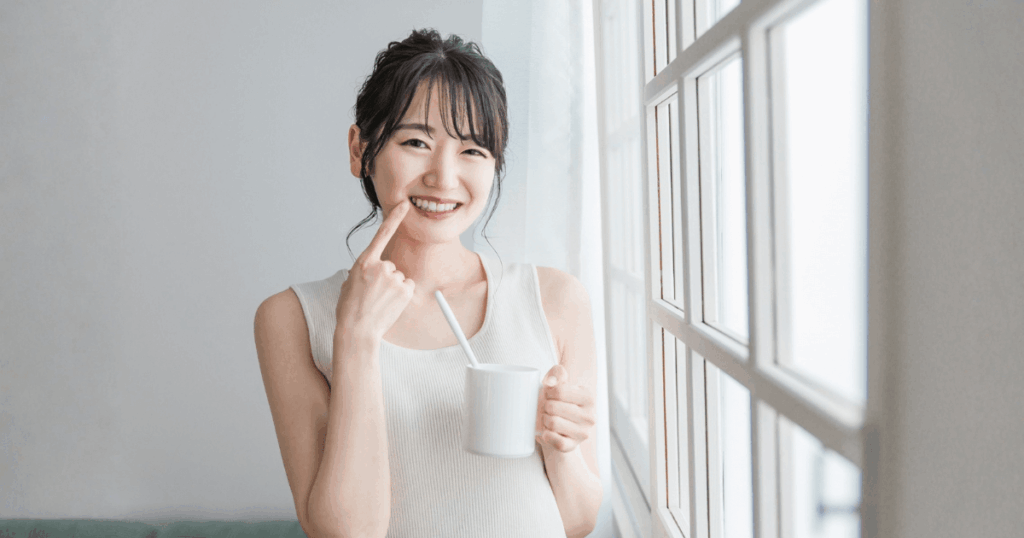 歯ブラシを持って笑顔を見せる女性。歯と歯の間の痛みを防ぐために日々の歯間ケアを続けるイメージ。