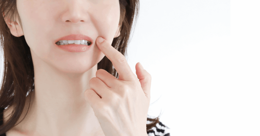 歯の痛みが続き、頬を押さえる女性。虫歯や神経の炎症などの可能性を示すイメージ。