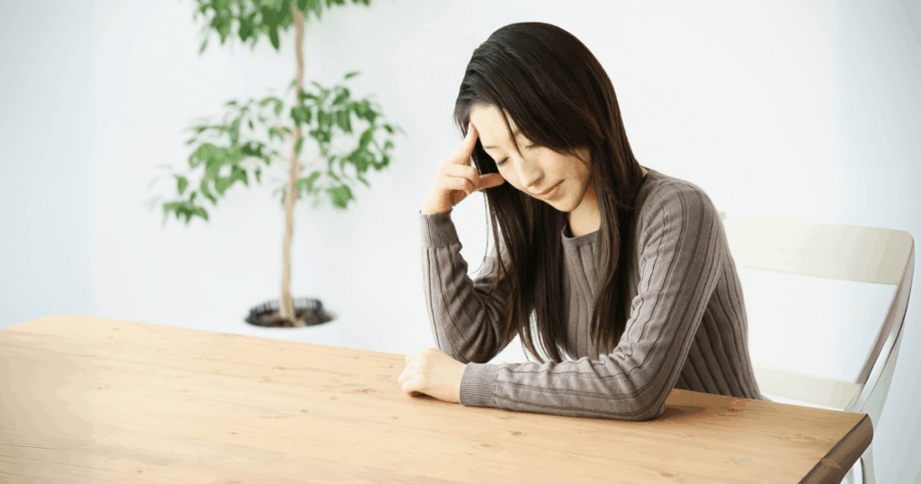 こめかみに手を当てて頭痛を感じる女性の写真