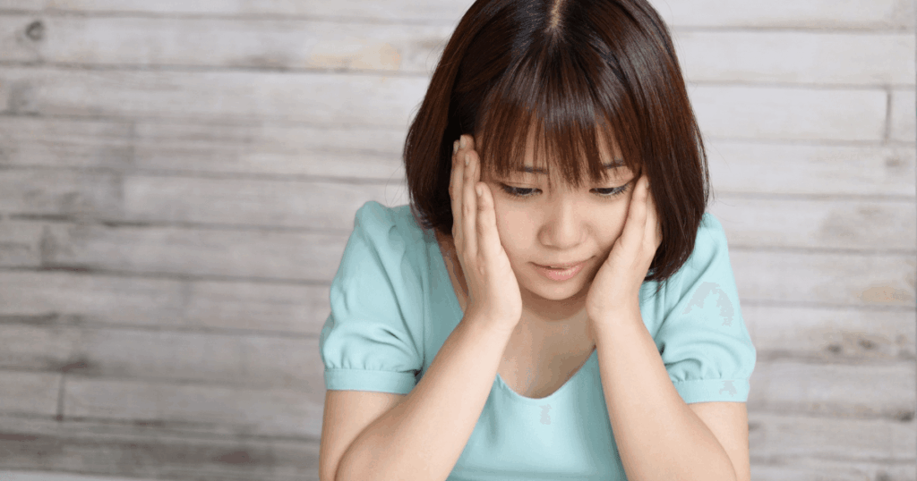 抜歯後の痛みや腫れに不安を感じている女性のイメージ写真