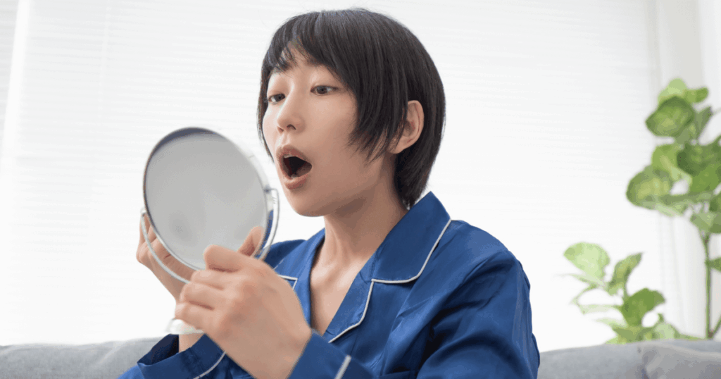 抜歯後に歯を入れず放置したときの口内変化を確認する女性のイメージ