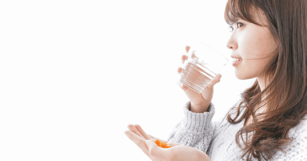歯の痛みをやわらげるために鎮痛薬を飲む女性