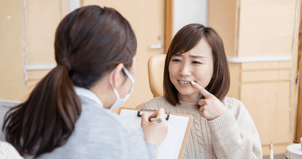 歯の痛みを訴えて歯科医に相談する女性