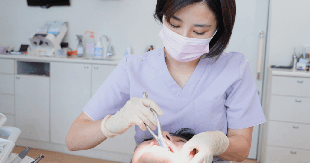 歯科医院で歯の治療を受けている患者と処置を行う歯科医のイメージ。抜歯の手順や麻酔の説明に関連
