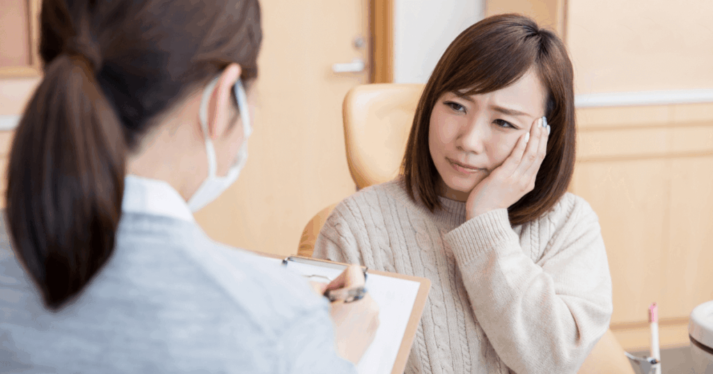 歯の痛みで歯科医に相談している女性