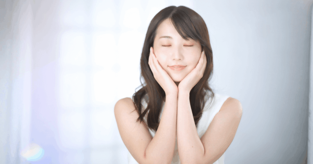 虫歯予防のために歯みがきを行い、口元を指して笑顔を見せる女性のイメージ