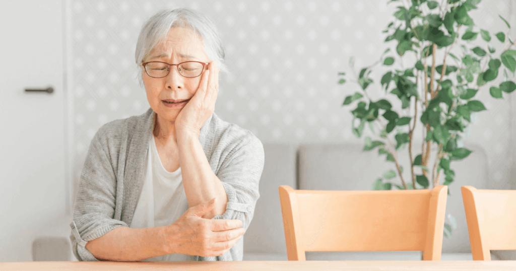 頬に手を当てて歯の痛みを感じる高齢女性