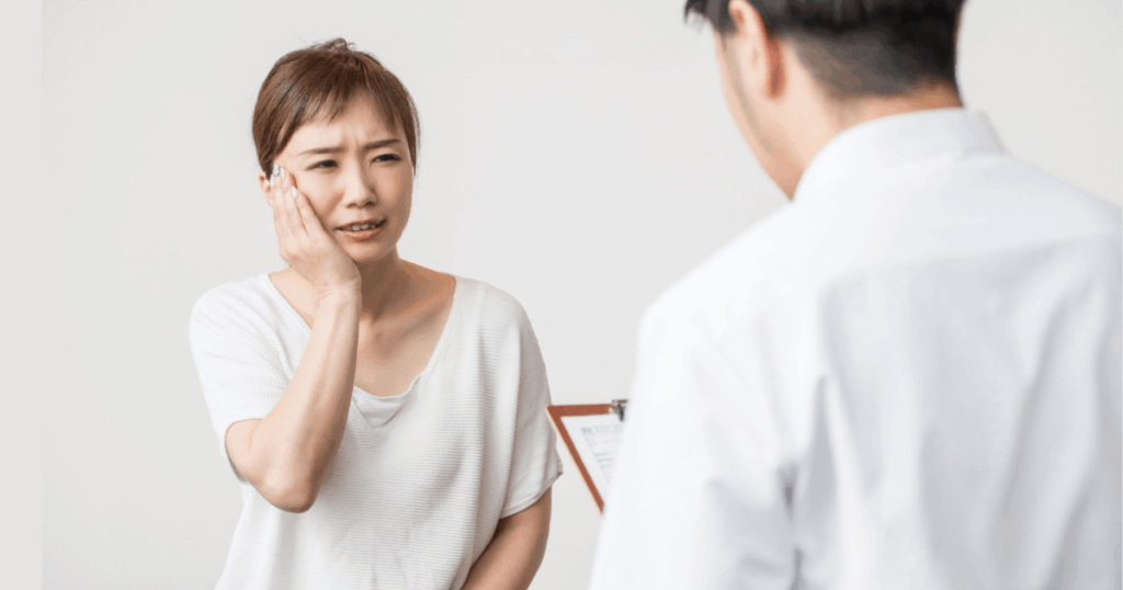 歯の痛みを訴えて歯科医に相談する女性