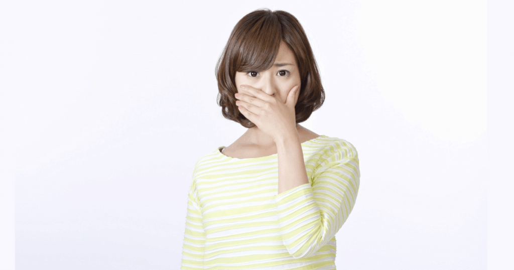 口を手で押さえて不安そうにする女性