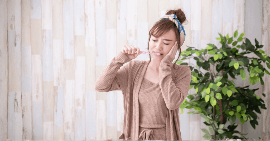 歯を磨きながら痛みを感じる女性