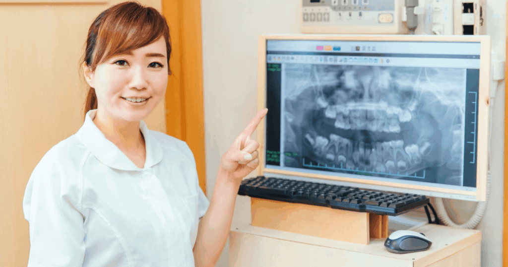 歯のレントゲン画像を指しながら説明する歯科スタッフの写真。治療の流れをイメージしたシーン。