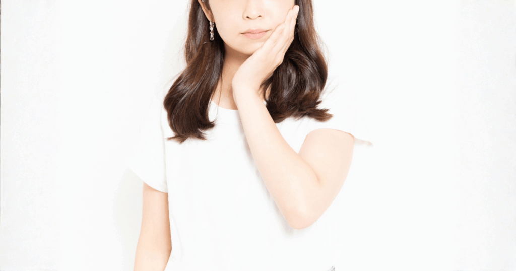 抜歯後の痛みが続き受診が必要か悩む女性