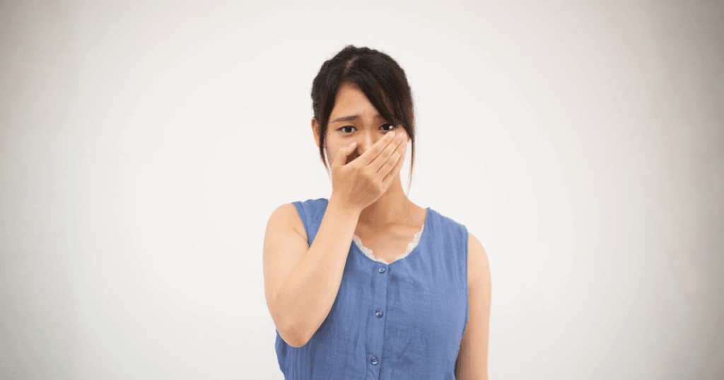 前歯を押すと痛みを感じて口を押さえる女性のイメージ