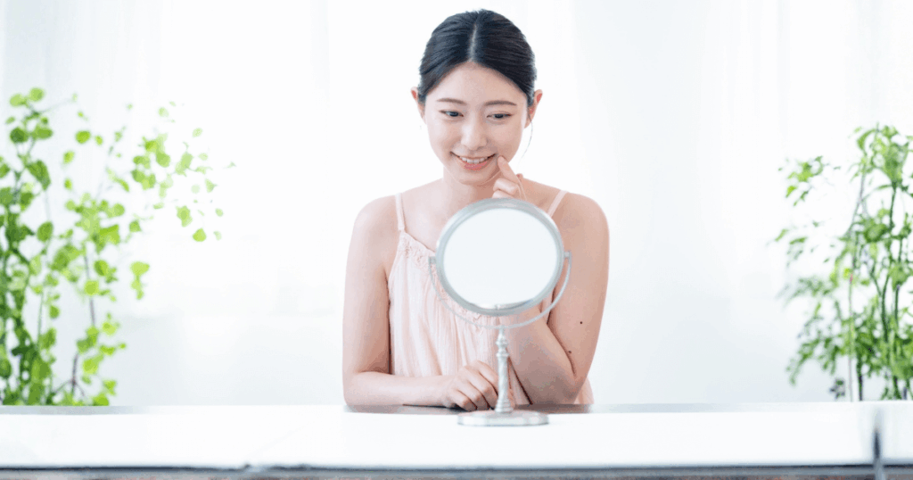 鏡を見ながら口元をチェックしている女性の写真。歯や口まわりのセルフケアを意識した生活習慣のイメージ。