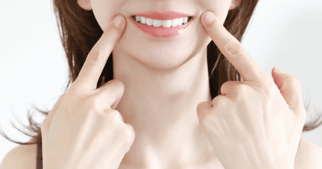 歯や頬を指で示している女性の写真。歯の痛みを和らげるセルフケアをイメージした画像。