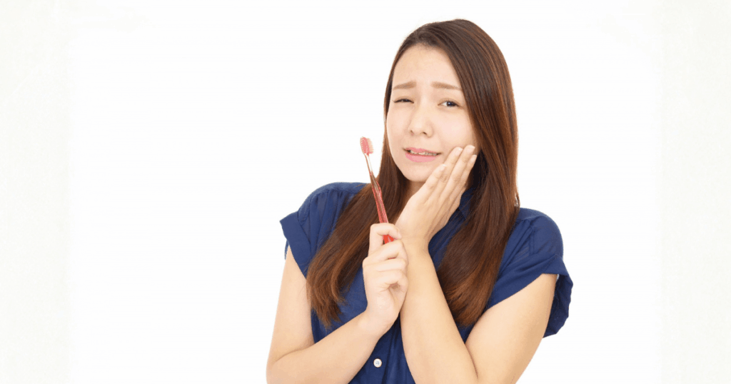 歯の下が痛く、頬を押さえている女性の写真。虫歯以外の原因で痛みが出ているイメージ。