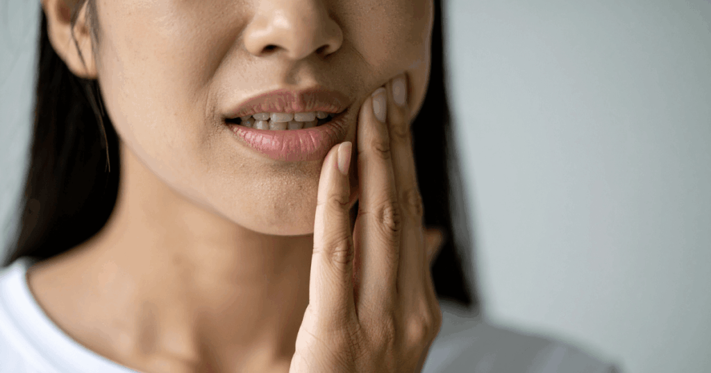 抜歯後にできる血餅について不安そうに頬を押さえる女性の口元の写真