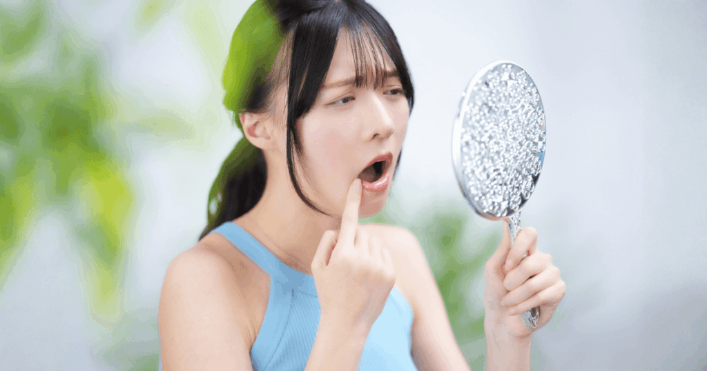 親知らずの抜歯後、痛みの状態を鏡で確認しながら様子を見るか受診するかを判断する女性のイメージ