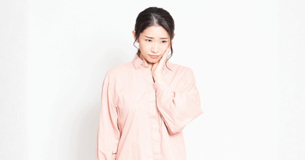 抜歯後の痛みや腫れに不安を感じている女性のイメージ画像