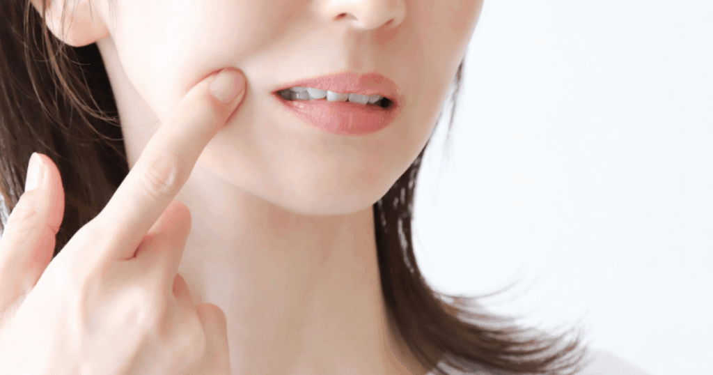 頬に触れながら歯のぐらつきを気にする大人の口元のイメージ