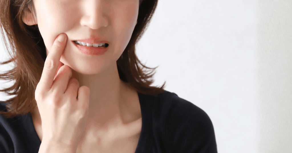 歯ぐきの違和感を感じて口元を気にする女性