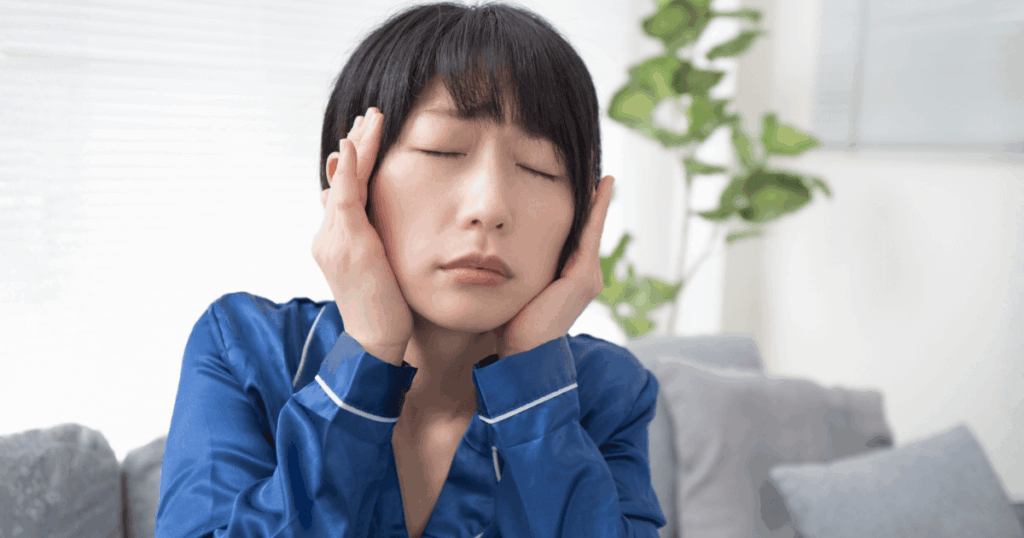 歯の痛みと頭痛が重なり、顔を押さえてつらそうにしている女性