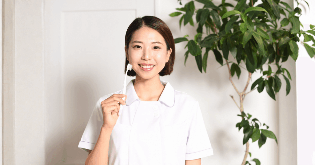 歯ブラシを持ち早期受診の大切さを説明する歯科スタッフ