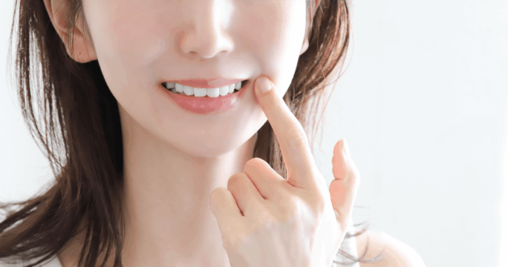 歯ぐきの状態を気にして頬に触れる女性の口元