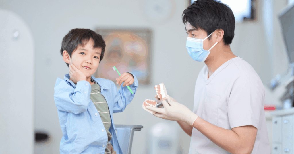 歯科医師が子どもに模型を使って説明し不安を和らげながら診療する様子
